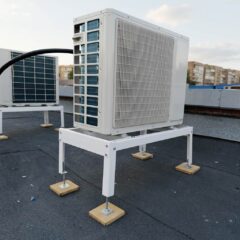 Рама для промышленного чиллера с установленным блоком на крыше здания. Белая металлическая конструкция с резиновыми прокладками.