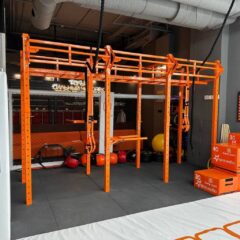 Спортивные площадки: крытая воркаут‑зона с оранжевыми металлическими рамами, разноуровневыми турниками, брусьями, боксерскими грушами, габариты и шаг между стойками, тип крепления подвесных элементов.