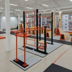 Спортивные площадки: крытая воркаут‑зона в помещении, разноуровневые турники и брусья, металлический каркас оранжево‑черного цвета, габариты и шаг между стойками, тип крепления к полу, расчет нагрузки на перекладины.