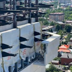 Ряд нестандартных металлоконструкций — декоративных парапетов на здании. Вид с высоты на городской пейзаж