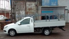 Белый бортовой автомобиль с установленным каркасом для кузова. Вид сбоку, металлическая конструкция с поперечинами