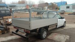 Белый бортовой автомобиль с каркасом для кузова, вид сзади. Металлическая рама, крепёжные элементы