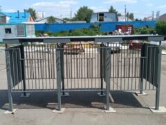 Фронтальный вид металлической контейнерной площадки для ТБО, видны глухие панели и решётчатое ограждение, конструкция на бетонном основании